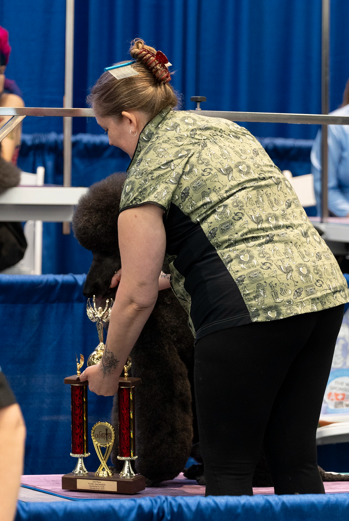 Person with a dog at a dog show, with trophies on a table